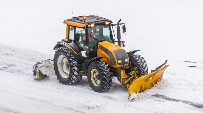 Gran máquina tractora de nieve en el trabajo en la carretera durante una tormenta de nieve en invierno